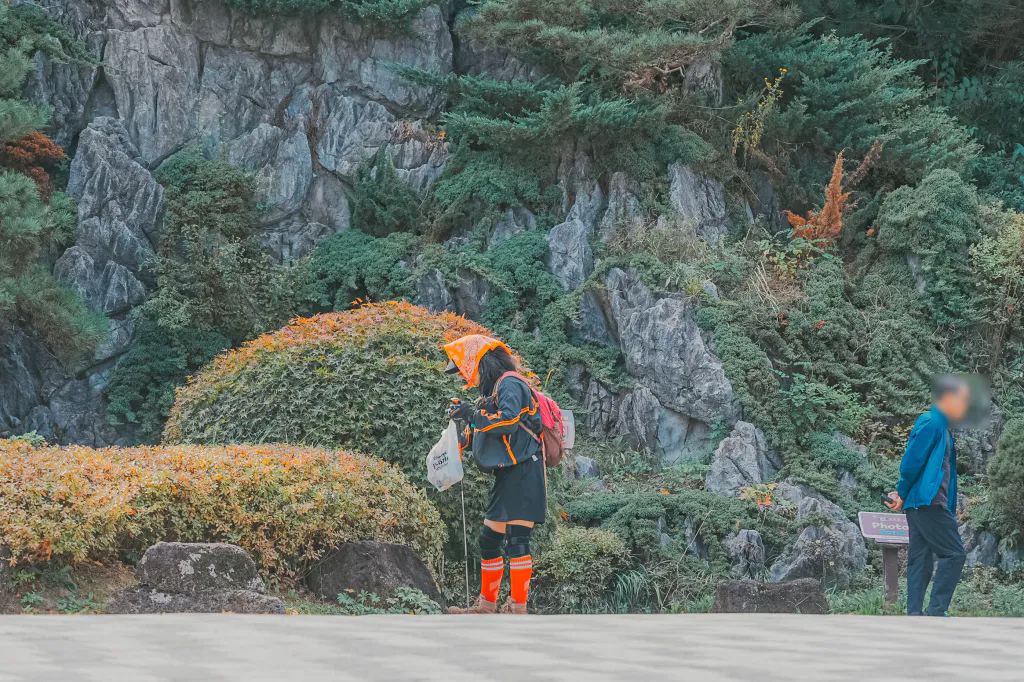 바위 정원 옆에서 쓰레기를 줍는 플로깅 참가자